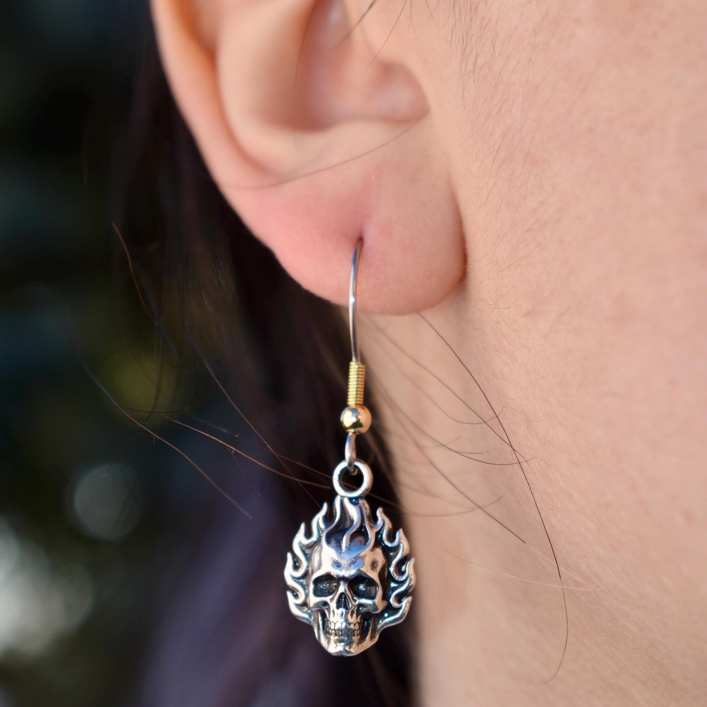 a woman wearing a Flaming Skull Charm earrings - Handcrafted .925 Sterling Silver Pendant for Bracelets and earrings by The Colorado Charm Company