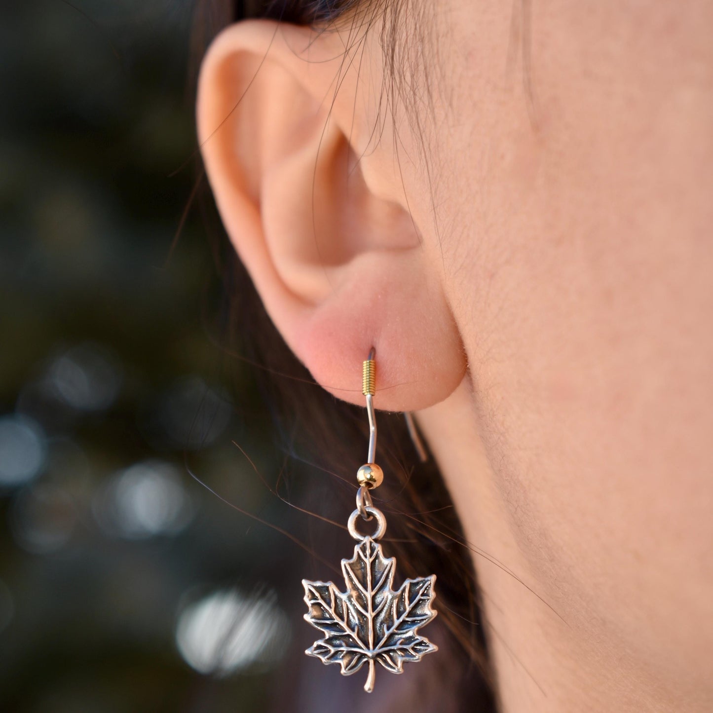 a woman wearing a detailed maple leaf Charm earrings - Handcrafted .925 Sterling Silver Pendant for Bracelets and earrings by The Colorado Charm Company