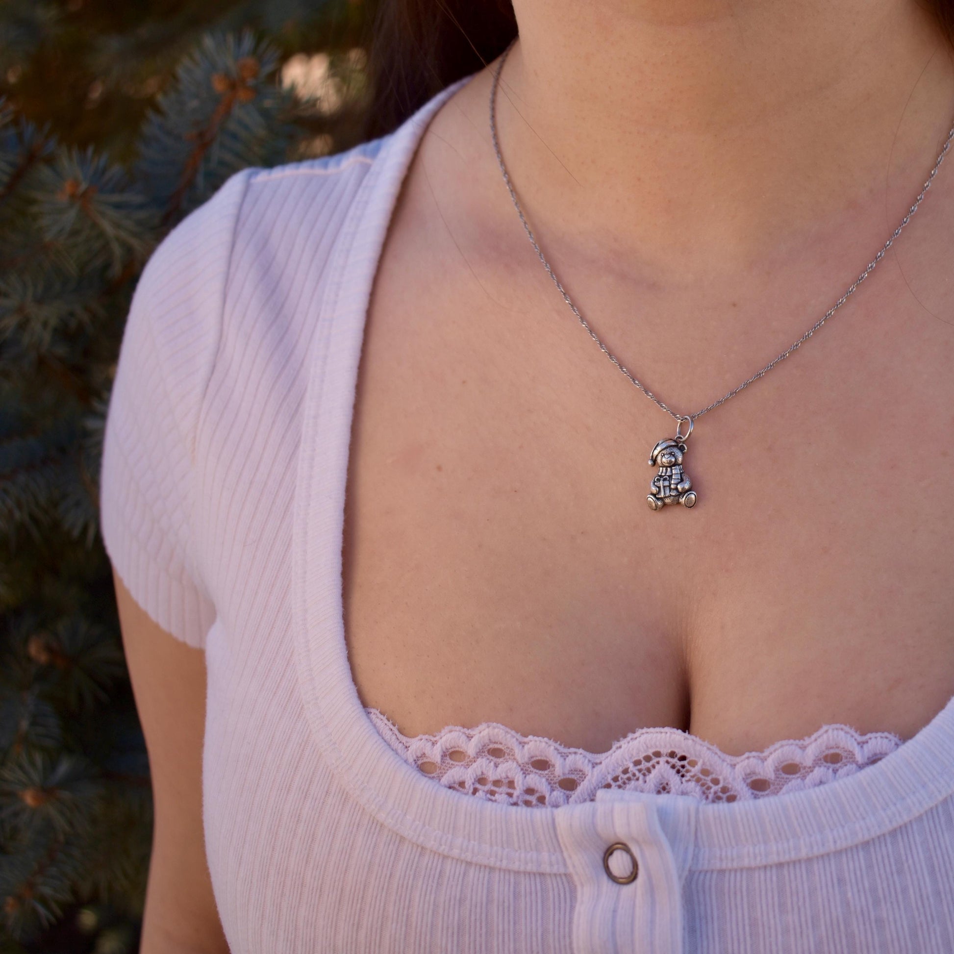 A woman wearing a Christmas teddy bear Charm on a necklace - Handcrafted .925 Sterling Silver Pendant for Bracelets and earrings by The Colorado Charm Company - Front view
