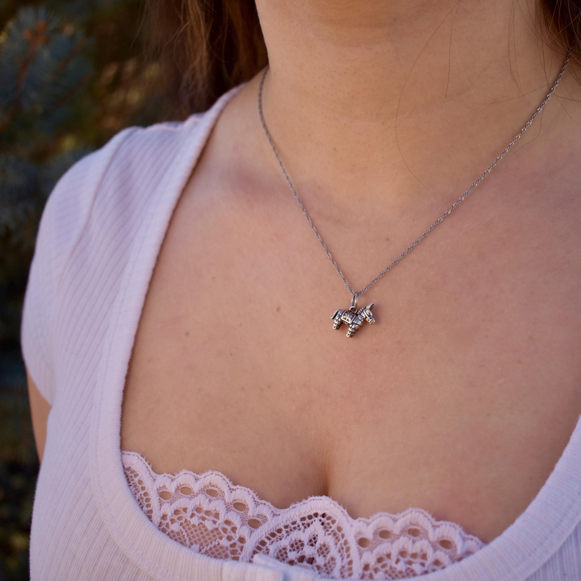 A woman wearing a donkey pinata Charm on a necklace - Handcrafted .925 Sterling Silver Pendant for Bracelets and earrings by The Colorado Charm Company