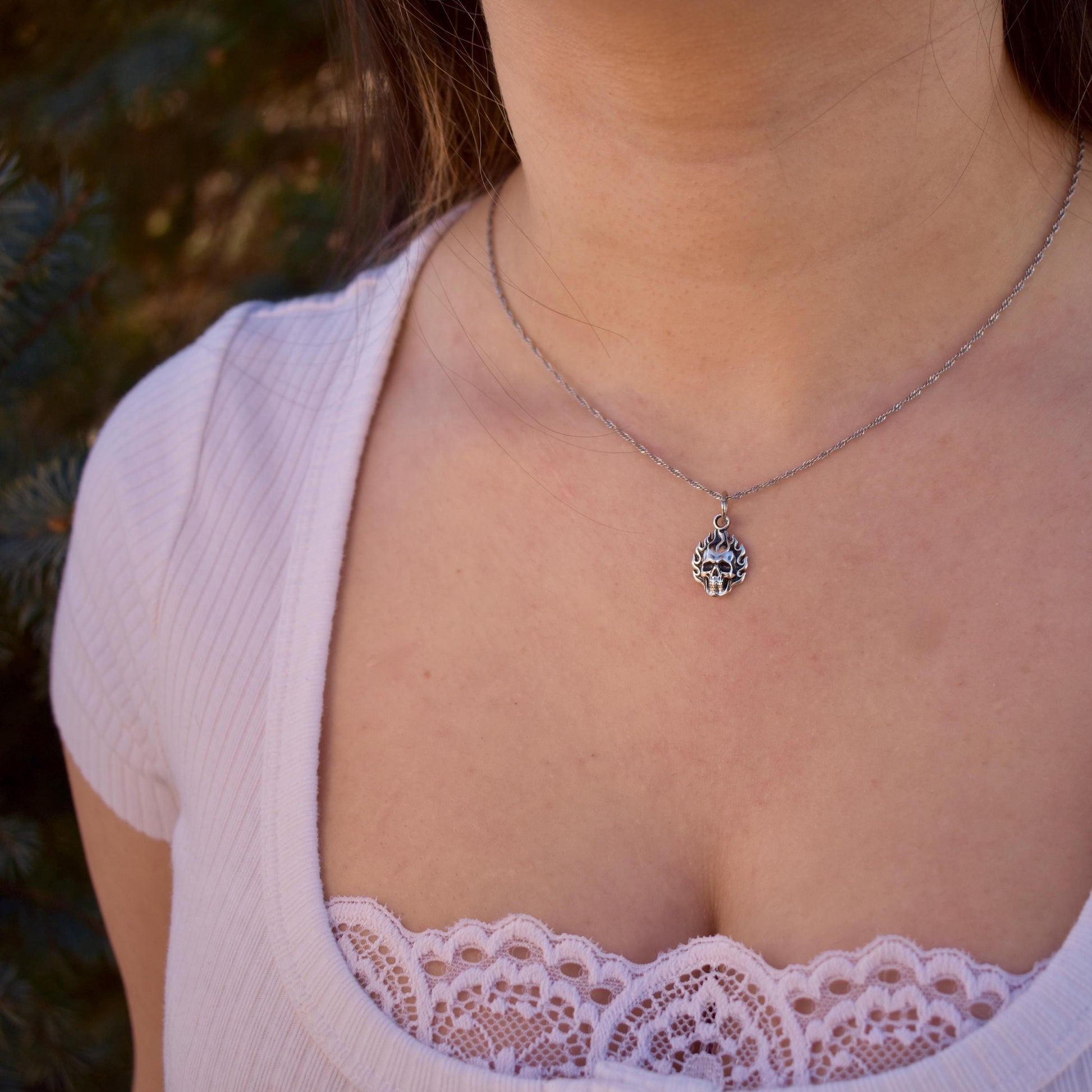 a woman wearing a Flaming Skull Charm on a necklace - Handcrafted .925 Sterling Silver Pendant for Bracelets and earrings by The Colorado Charm Company 