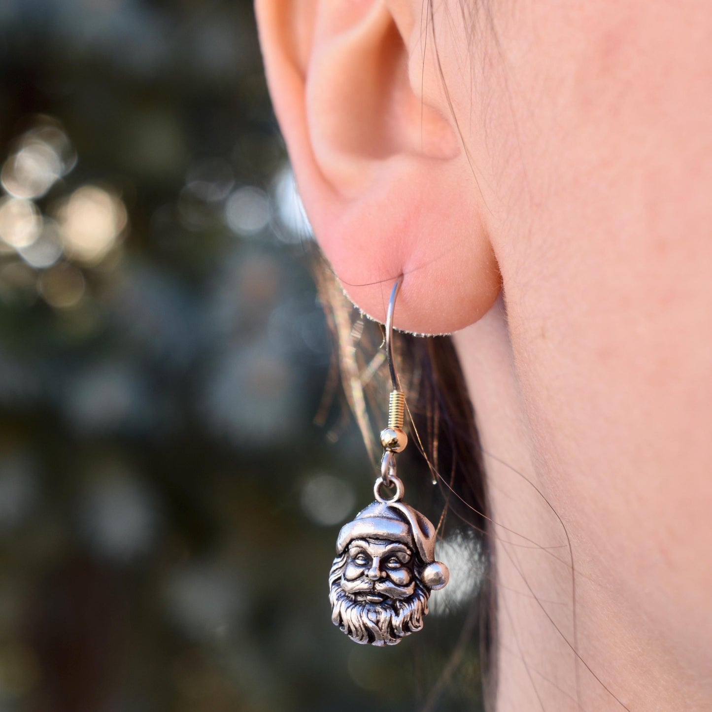 A Woman Wearing a Classic Santa Claus Charm as earrings- Handcrafted .925 Sterling Silver Pendant for Bracelets and earrings by The Colorado Charm Company